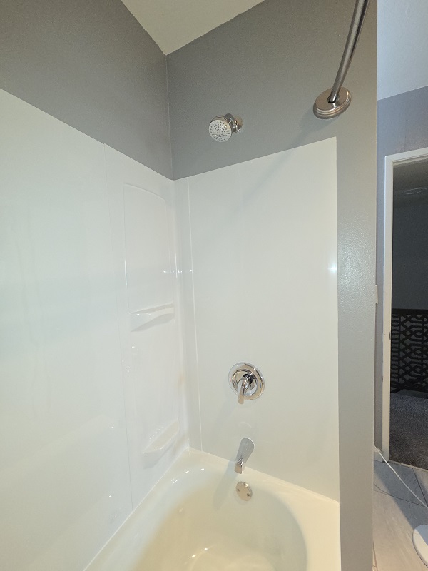 White acrylic tub and shower remodel with updated fixtures and clean wall panels.