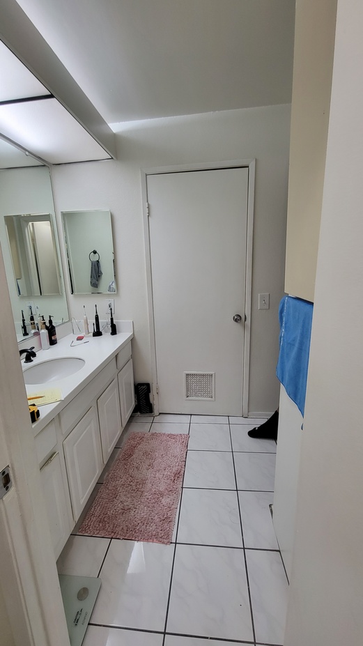 Outdated bathroom layout with builder-grade vanity and tile flooring before remodel.