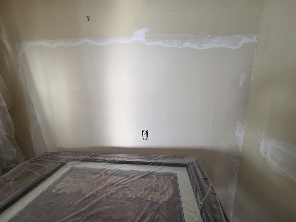 Drywall patch and skim coat applied to interior wall during kitchen repair and repaint preparation.