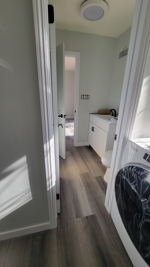 Remodeled hallway and laundry area with new flooring, fresh paint, and updated interior finishes.