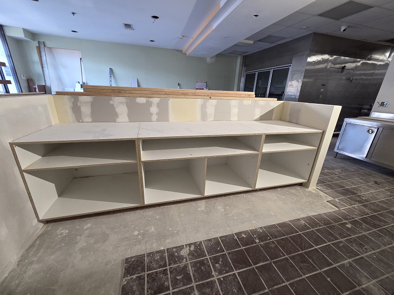 Custom commercial shelving installation during interior build-out and drywall finishing.