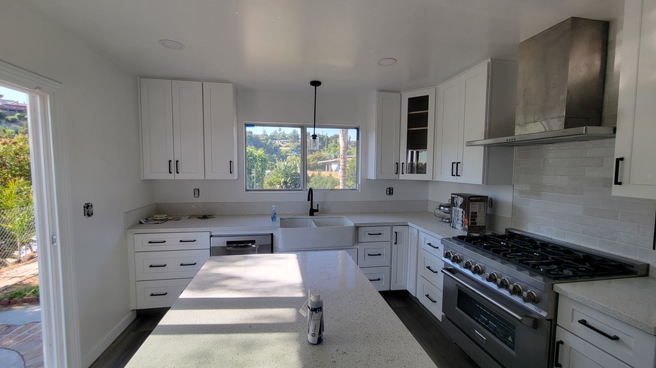 Bright white kitchen remodel featuring quartz countertops, shaker cabinets, and pendant lighting.