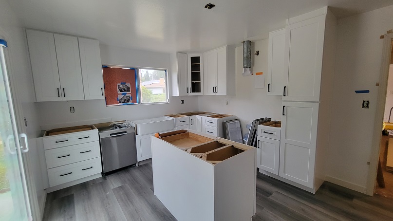 Kitchen renovation in progress with new cabinets installed and appliance placement prepared.